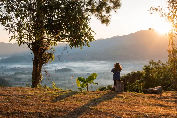Jovem mulher assistindo nascer do sol no alto da montanha em Phu Lung ka — Fotografia de Stock