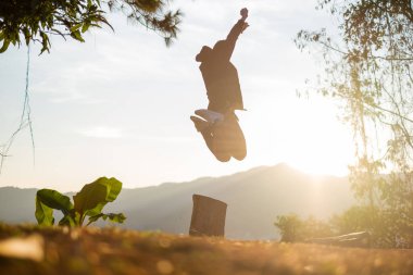 Genç adam atlama gündoğumu arka planda Dağı'nda Phu akciğer ka, Tayland