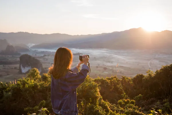 Ung kvinna att ta foton av soluppgång i berg på Phu Lung ka, Thailand — Stockfoto