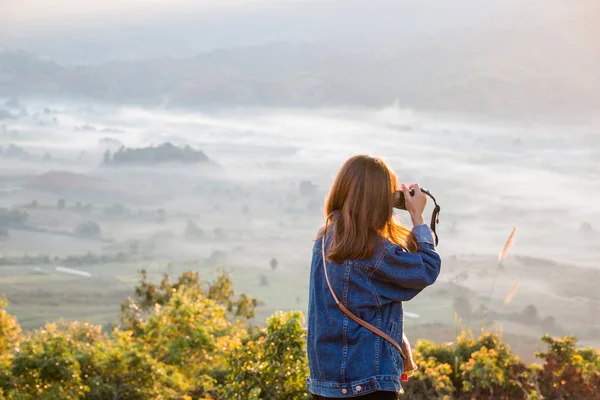 Ung kvinna att ta foton av soluppgång i berg på Phu Lung ka, Thailand — Stockfoto