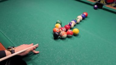 Genç adam ok ters yönde bilardo topları ile vuruyor. Çelişki kavramı.