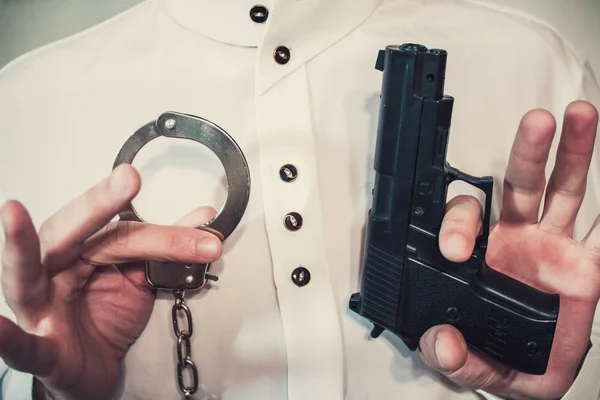 Молодой бизнесмен держит наручники и заряженный пистолет. — стоковое фото