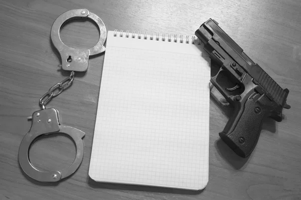Handgun algemas e bloco de notas sobre a mesa com espaço de cópia fotografia em preto e branco — Fotografia de Stock