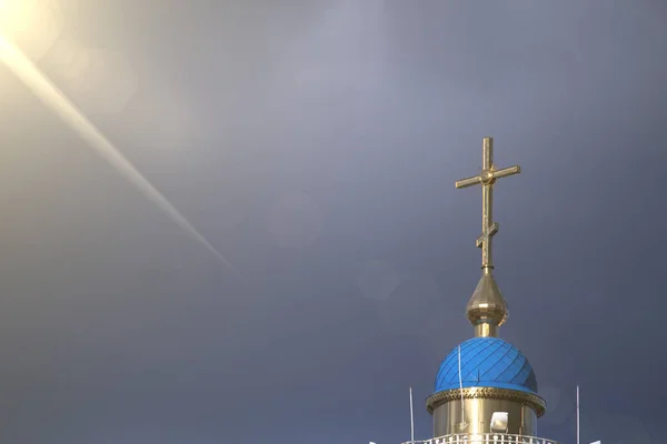 Великий християнський хрест на якому падає промінь сонця крізь хмари — стокове фото