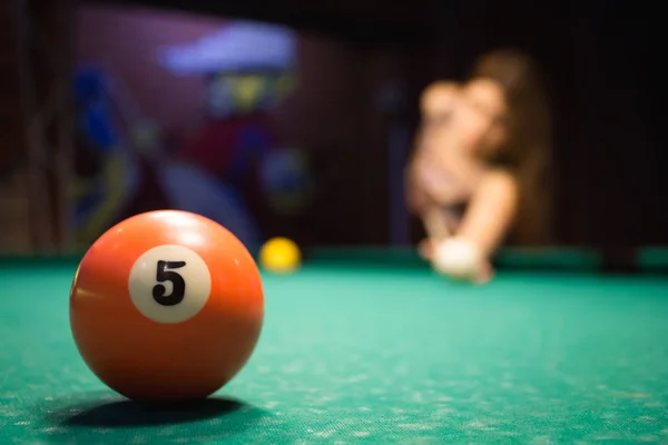 A girl is playing billiards in a dark billiard club. — Stock Photo, Image