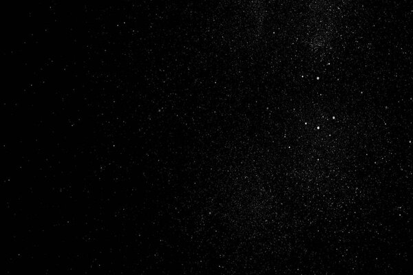 White particles and ink slowly moving in water on black background