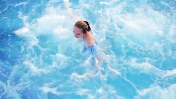 Joven hermosa chica está nadando en la piscina en la bañera de hidromasaje — Vídeos de Stock