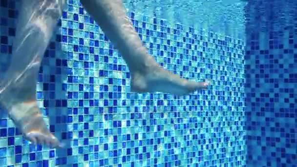 Las piernas femeninas de la belleza con una pedicura bajo el agua, balanceándose en la piscina escena exótica de cámara lenta de disparo — Vídeos de Stock
