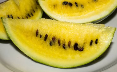 Sarı bir karpuz bir dilim bir plaka üzerinde yatıyor