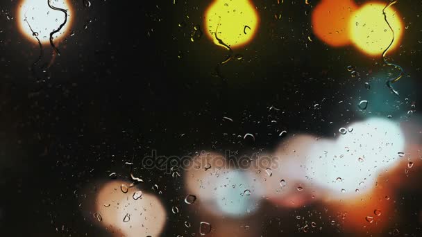 Gotas de lluvia en una ventana de coche con fondo borroso de semáforos en la calle — Vídeos de Stock