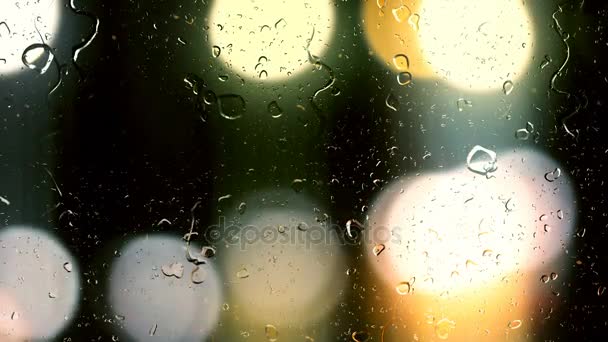 Gotas de lluvia fluyen por el vidrio sobre el fondo bokeh de los coches en movimiento — Vídeos de Stock