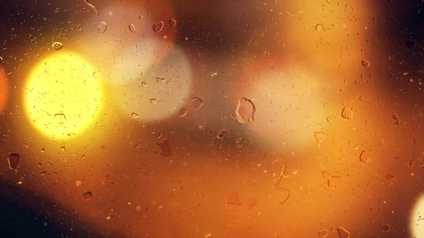 Gotas de lluvia fluyen por el vidrio sobre el fondo bokeh de los coches en movimiento — Foto de Stock