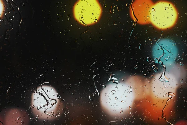 Yağmur damlaları bir araba penceresindeki güzel sokak trafik ışıkları arka plan bulanık