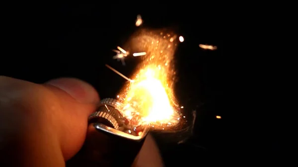 Использование зажигалки руки на черном фоне — стоковое фото