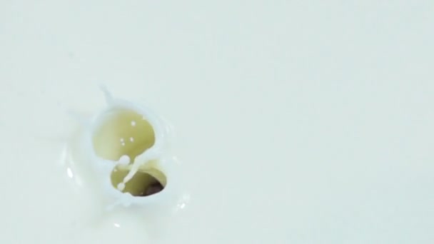 Одна клюква падает в молоко с йогуртом в замедленной съемке — стоковое видео