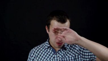 Bir ağlayan silme gözü yaşlı genç adam ağır çekimde siyah bir zemin üzerine