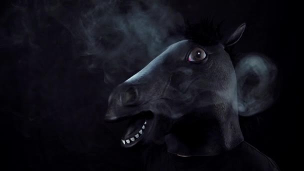男子在一匹马的面具在黑色背景下缓慢运动的烟雾 — 图库视频影像