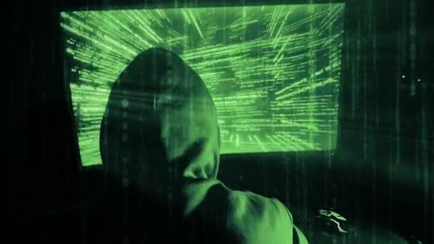 Ένας χάκερ ο άνθρωπος σε μια κουκούλα σε ένα σκοτεινό δωμάτιο που λειτουργεί με τον κωδικό προγράμματος — Αρχείο Βίντεο