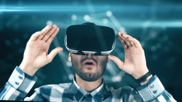 En ung man med ett skägg i glas av virtuell verklighet på en teknisk bakgrund — Stockvideo