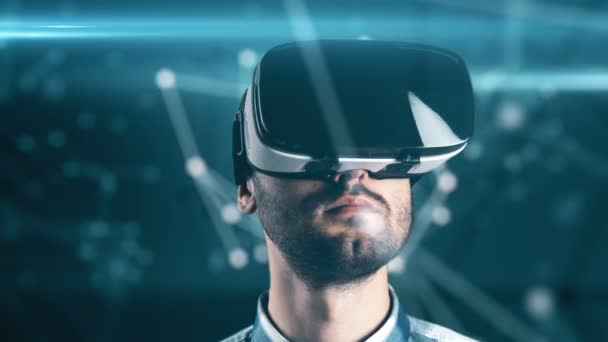 Молодой человек с бородой в очках виртуальной реальности на технологическом фоне — стоковое видео