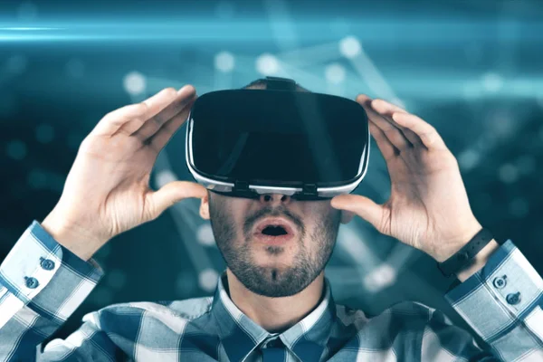 Mladý muž s bradkou v brýle virtuální reality na technologické zázemí — Stock fotografie