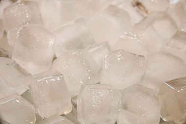 Beyaz bir arka plan üzerinde yavaş çekimde eriyen berrak sudan buz küplerinin makro çekimi. Konsept: saf dağ kaynak suyu, buz, kokteyller, taze ve dondurulmuş gıdalar.