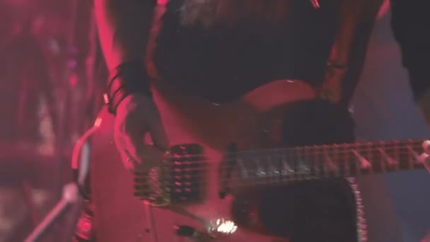 Um guitarrista virtuoso tocando uma guitarra elétrica no palco com luzes LED piscando . — Vídeo de Stock