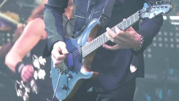 Um guitarrista virtuoso tocando uma guitarra elétrica no palco com luzes LED piscando . — Vídeo de Stock