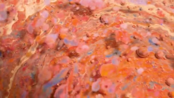 Красочные акриловые краски смешиваются в красивых узорах. Масляные чернила коралловых, оранжевых, красных и других цветов разбросаны по поверхности и смешиваются, создавая удивительные текстуры и дизайн. Абстрактные пузыри — стоковое видео