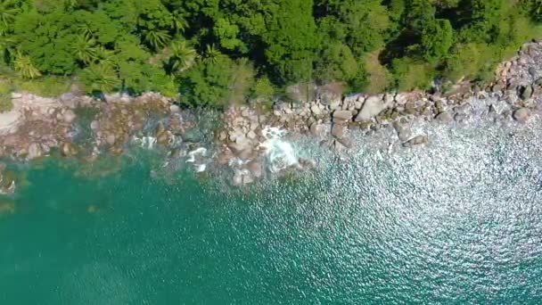 Felfelé haladva az óceán kék hullámai lezuhannak a part menti sziklán. Légi felvétel 4k lassított felvételen — Stock videók