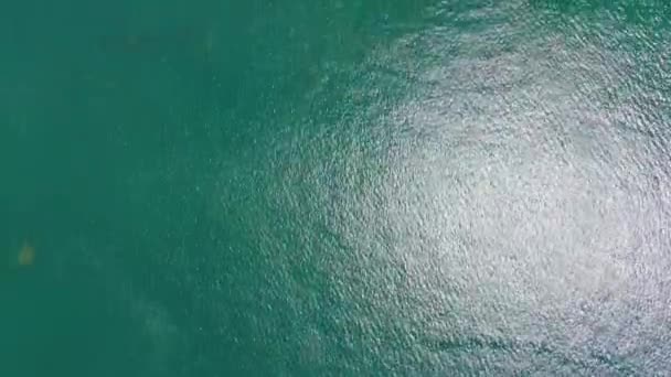 Felfelé haladva az óceán kék hullámai lezuhannak a part menti sziklán. Légi felvétel 4k — Stock videók