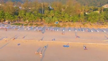PHUKET, THAILAND - 15 MAR 2020: Karon sahilinde gün batımı, insanlar denizde yüzer ve güneşlenir, tatil köyü kumsalı. Karantina covid-19 nedeniyle plajları kapatmadan birkaç gün önce. Hava 4k görüntüsü