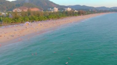 Karon sahilinde gün batımı, insanlar denizde yüzer, güneşlenir, plajda tatil yapar. Karantina covid-19 nedeniyle plajları kapatmadan birkaç gün önce. Hava 4k görüntüsü