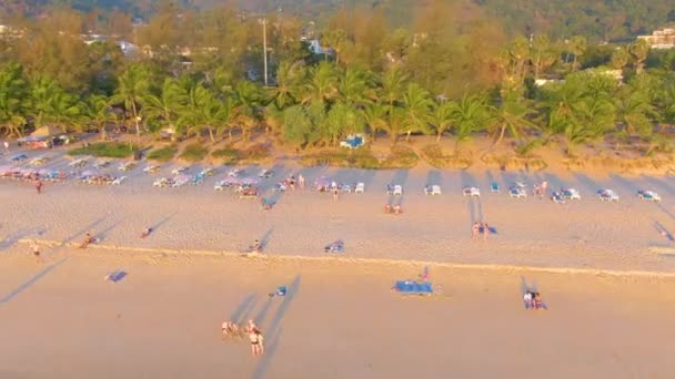 PHUKET, THAILAND - 15 MAR 2020：日落在卡隆海滩上，人们在海里游泳，日光浴在度假胜地海滩上。几天前，关闭海滩由于检疫鳕鱼-19 。Aerial 4k footage — 图库视频影像