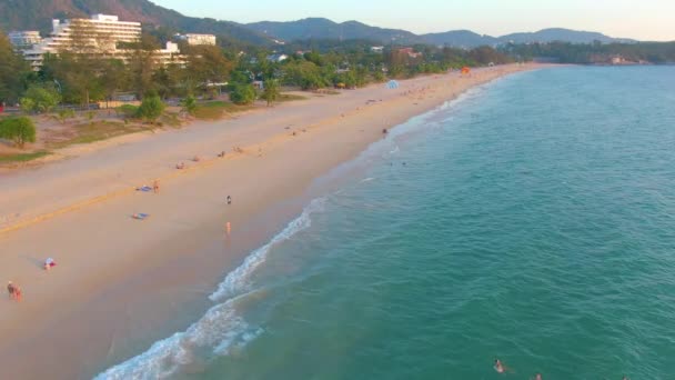 Pôr do sol na praia de Karon, as pessoas nadam no mar e tomar sol, praia resort. Poucos dias antes de fechar praias devido à quarentena covid-19. Imagens aéreas 4k — Vídeo de Stock