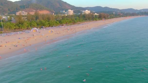 Sonnenuntergang am Strand von Karon, Menschen schwimmen im Meer und sonnen sich am Strand des Resorts. Ein paar Tage vor der Schließung der Strände aufgrund der Quarantäne covid-19. Luftaufnahmen in 4k — Stockvideo
