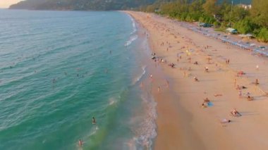 Karon sahilinde gün batımı, insanlar denizde yüzer, güneşlenir, plajda tatil yapar. Karantina covid-19 nedeniyle plajları kapatmadan birkaç gün önce. Hava 4k görüntüsü