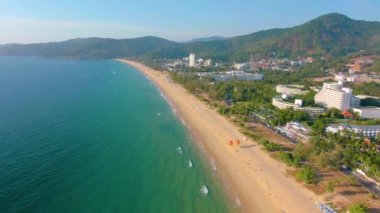 Hava 4k manzarası tropikal mavi okyanusun üzerinden güzel yeşil dağlara ve beyaz kumlu plaja doğru uçuyor. Tayland. Phuket. Karon plajı. Palms plajı. Ada manzaralı. Güzel tatil yeri.