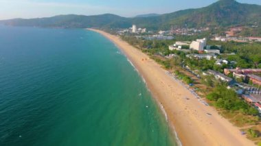 Hava 4k manzarası tropikal mavi okyanusun üzerinden güzel yeşil dağlara ve beyaz kumlu plaja doğru uçuyor. Tayland. Phuket. Karon plajı. Palms plajı. Ada manzaralı. Güzel tatil yeri.