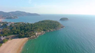 Hava 4k manzarası tropikal mavi okyanusun üzerinden güzel yeşil dağlara ve beyaz kumlu plaja doğru uçuyor. Tayland. Phuket. Karon plajı. Palms plajı. Ada manzaralı. Güzel tatil yeri.