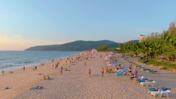 PHUKET, THAILAND - 15 MAR 2020: Pôr do sol na praia de Karon, as pessoas nadam no mar e se bronzeiam, praia resort. Poucos dias antes de fechar praias devido à quarentena covid-19. Imagens aéreas 4k — Vídeo de Stock