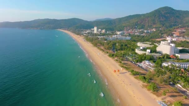 Flygfoto 4k utsikt flyger över tropiskt blått hav mot vackra gröna berg och vit sandstrand. Thailand. Det är Phuket. Stranden Karon. Palmstranden. Öns ovanifrån. Vacker semesterort. — Stockvideo