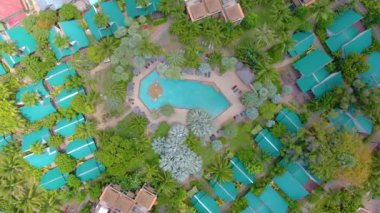 Lüks otel, tepeden tırnağa insansız hava aracı ile havadan 4k görüntüsü. Palmiye ağaçları, güneş gölgesi, güneş şemsiyesi, jakuzi. Su kaydırağı Havuzlar, bahçe ve plaj yukarıdan.