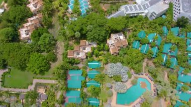 Grand Hyatt Kauai Lüks Otel Tatil Köyü. İHA 'yla havadan 4k' lik görüntü. Palmiye ağaçları, güneşlik, şemsiye, jakuzi. Su kaydırağı Havuzlar, bahçe, kıyı şeridi ve plaj yukarıdan.