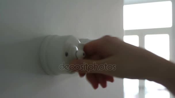 Eine Frau schaltet in einem Haus einen Lichtschalter ein und aus — Stockvideo