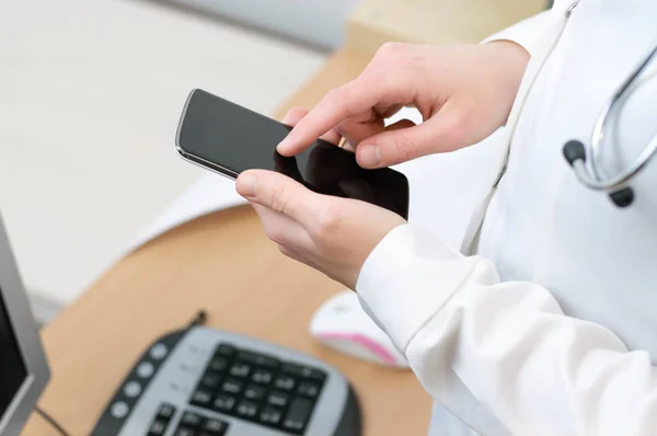 एक महिला डॉक्टर स्मार्टफ़ोन पर पाठ कर रहा है — स्टॉक फ़ोटो, इमेज
