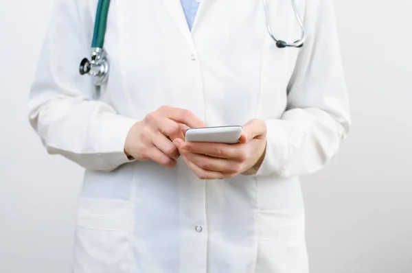 Жінка-лікар смс на смартфоні — стокове фото