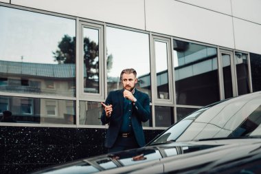 Şehir caddesinde vaping takım elbiseli şık sakallı adam 