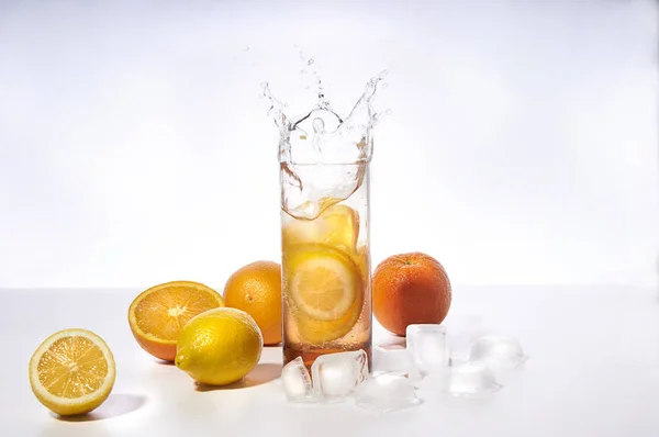 orange juice splashing in a glass decorated with oranges, ice cubes and berries. splashing  liquid in glass isolated on white