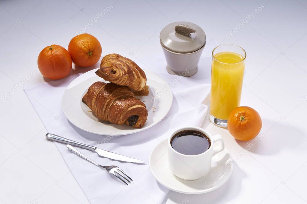 Fresh croissants, orange juice, coffee and oranges. Continental breakfast on white table